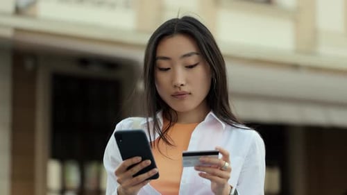 Asian Woman Makes Online Payments Through the Internet From Bank Card on Smartphone