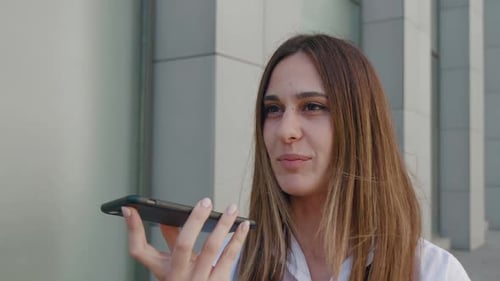Young Woman Using Voice Command on Smartphone in City