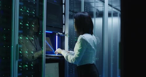 Female Technician Works on a Laptop in a Data Center