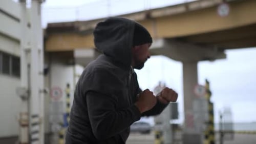 Sporty Muscular Active Man in Comfortable Clothes Boxing Practising in Industrial Zone Under