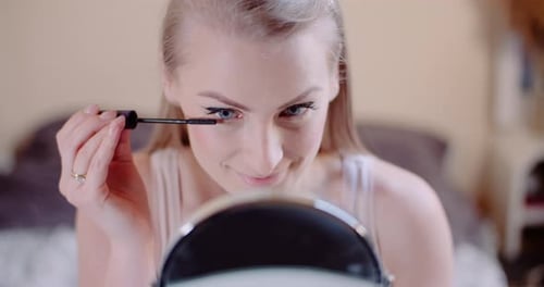 Woman Applying Mascara in Front of Mirror