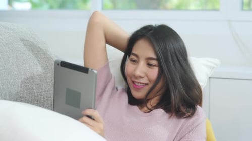 Woman Using Tablet Relaxing on Couch at Home