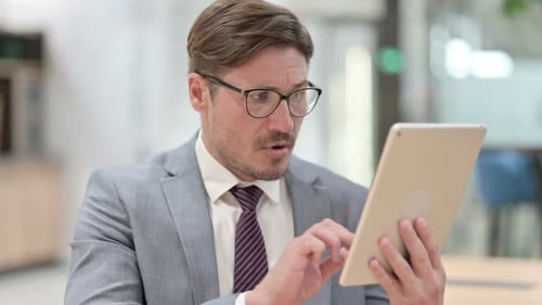Man Using Tablet Reacts with Surprise in Office