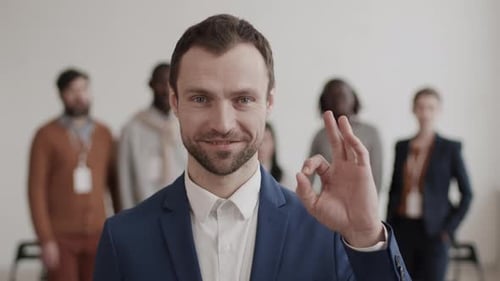 Homme d'affaires caucasien montrant un panneau OK posant