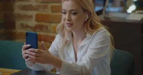 Young Woman Making Video Call Chat Online on Mobile Phone at Cafe