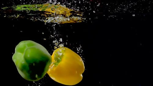 Colorful Bell Peppers Dropping into Water on Black Background