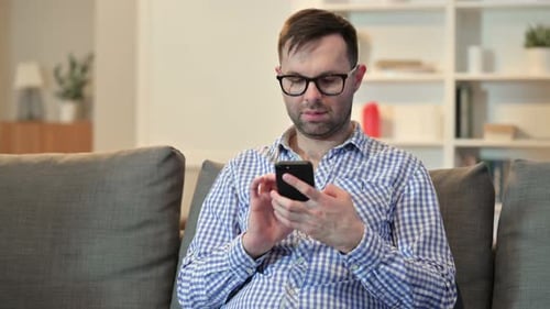 Serious Young Man Using Smartphone at Home