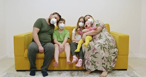 Family Wearing Protective Masks Sitting on Yellow Couch