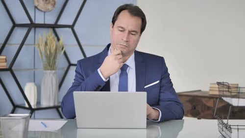 Pensive Businessman Thinking and Working on Laptop