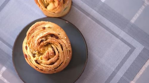 Junge Frau legt frisch gebackenen Osterkuchen Cruffin auf den Küchentisch