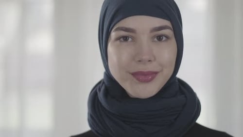 Porträt einer unabhängigen jungen muslimischen Frau, die ernsthaft selbstbewusst in die Kamera schaut und traditionell trägt