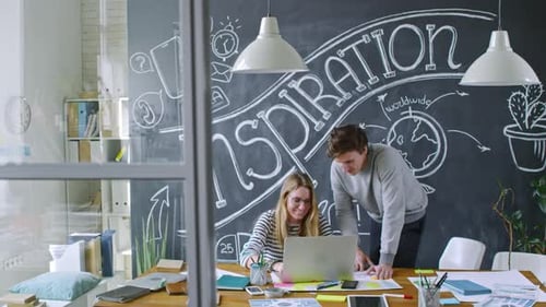 Cheerful Colleagues Working Together on Laptop and Chatting at Office Desk