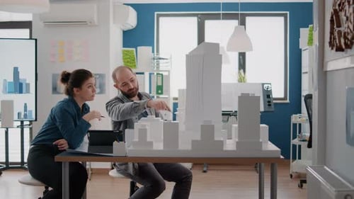 Workmates Looking at Tablet and Building Model to Get Inspiration for Urban Project
