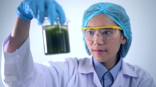 Scientist Inspecting Green Liquid in Lab