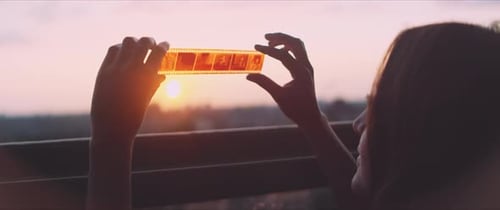 Woman Holding Up Film Strip at Sunset