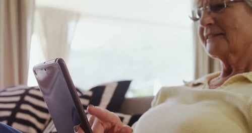 Senior Woman Using Tablet on Couch Indoors