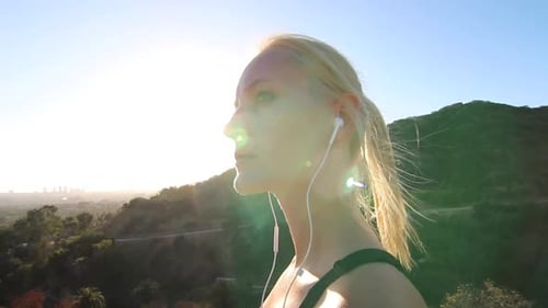 A young woman runner takes a break from running to catch her breath and admire the view.