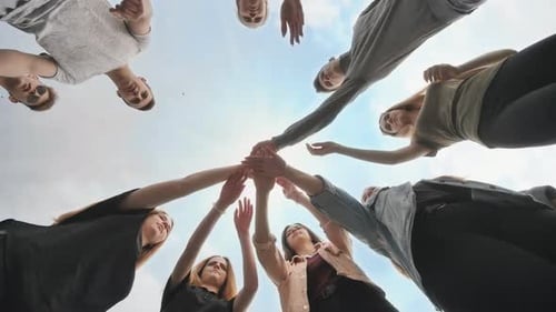 Friends Joining Hands in Unity Underneath Blue Sky