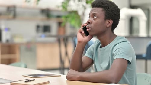 Young Adult Talking on Smartphone at Desk