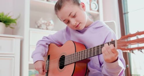 Young Girl Plays Guitar in Bright Room
