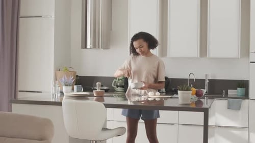 Young Adult Cooking in Bright Modern Kitchen
