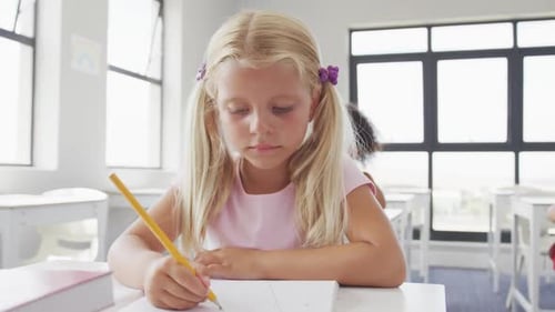 Video of happy caucasian girl sitting at school desk and learning
