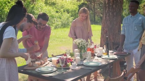 Friends Gather Around Outdoor Picnic Table on Sunny Day