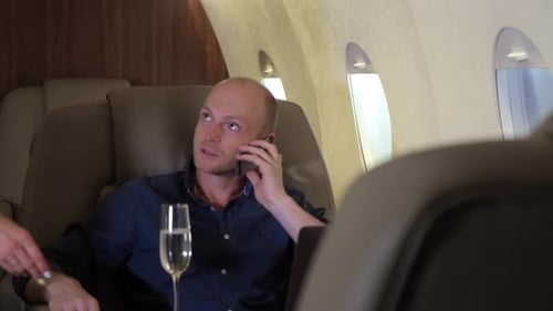 Woman Offers Champagne to Man in Private Jet