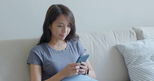 Woman Using Mobile Phone While Sitting on Sofa
