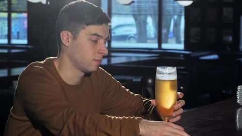 Junger Mann lächelt in die Kamera, nachdem er köstliches Bier aus einem Glas getrunken hat