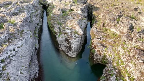 Fork of a narrow mountain river flowing through rocky landscape. Stream bed cut deep into rock.