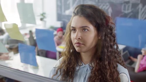 Caucasian Woman Arranging Reminders on Glass Wall in Office