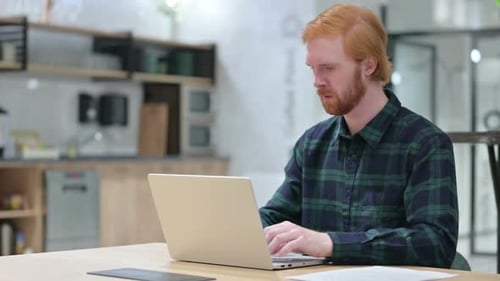 Young Adult Man Working on Laptop at Desk