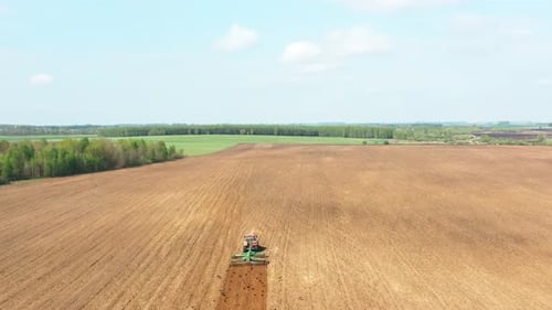 Tractor con vista plana desde el aire, campo de arado en la temporada de primavera
