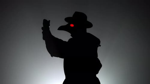 Plague Doctor with Crow-like Mask Puts on Gloves Isolated on Black Smoke Background. Creepy Mask