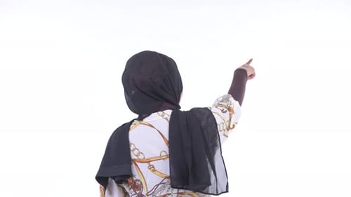 Vista posterior de la joven mujer musulmana africana señalando con el dedo
