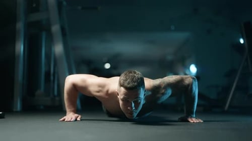 A Handsome Young Muscular Sportsman is Doing Exercise on a Fitness Machine in the Gym