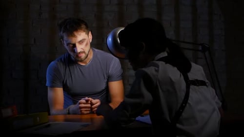 Man in Handcuffs Being Interrogated in Dark Room