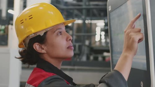Woman Using Touchscreen Monitor in Factory Setting