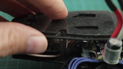 Extreme Nahaufnahme der Hände eines jungen Mannes beim Zusammenbau der FPV-Renndrohne mit einem Schraubenzieher.