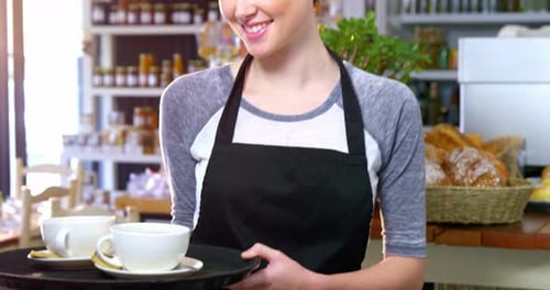 Kellnerin hält Kaffeetassen in einem Tablett