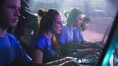 Focused Young Adults Playing Computer Games in Dark Room