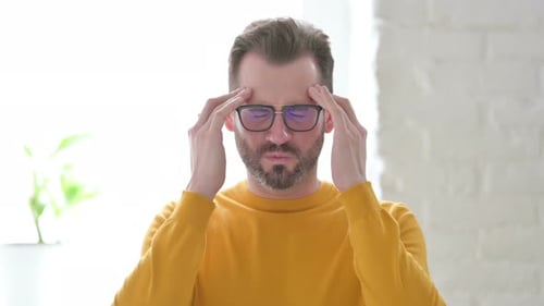 Man with Headache Rubbing Temples Indoors