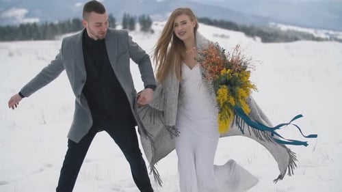 Newlyweds Walking in Snowy Winter Mountain Landscape
