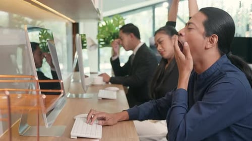Tired businessteam yawning during working on computer sitting at desk office