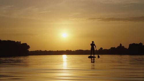Paddleboarding at Sunset on Calm Lake Waters