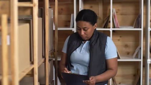 Black Female Post Office Clerk Checking Parcels on Racks