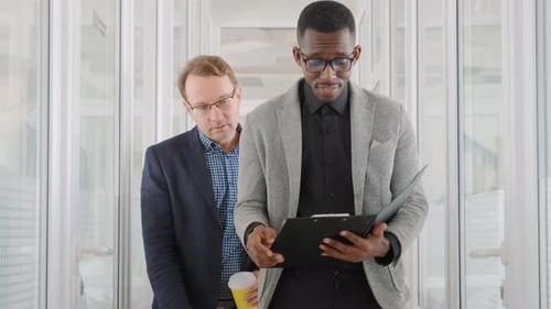 Two Men of Different Races and Ethnicities Walk in Office and Discuss Business