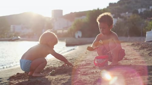 Children Play in the Sand on the Beach Near the Sea