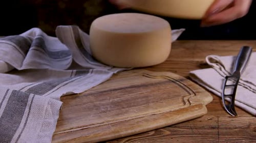 Women hands put a wheel of fresh homemade cheese on a wooden board close up
